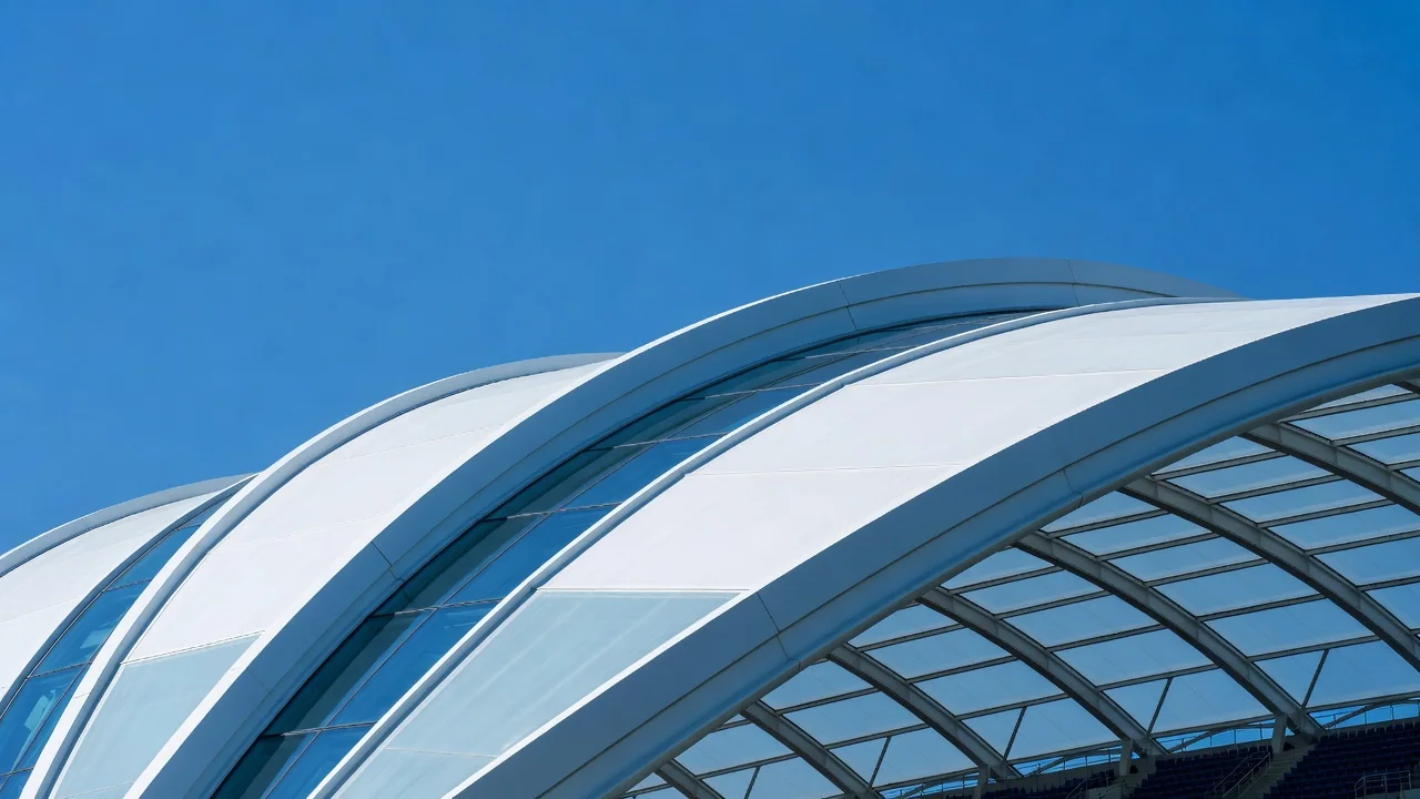 Teto curvo de estádio moderno recortado contra o céu azul, sem pessoas