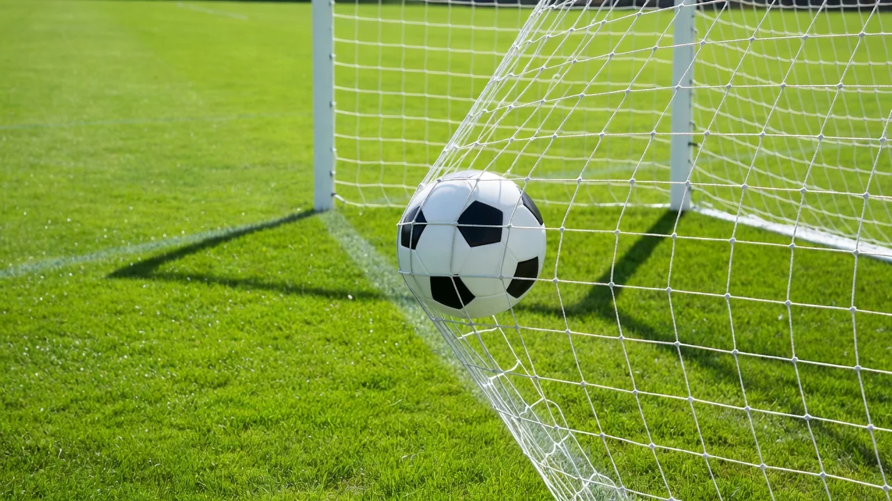 Bola de futebol atingindo o fundo da rede, movimento congelado, gramado ensolarado